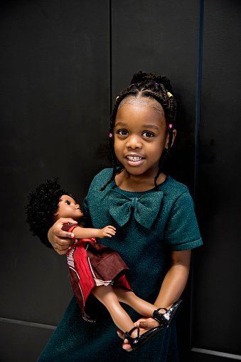 Portrait of black little girl with same skin colour doll.